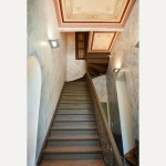 The primary entrance foyer features the original wooden staircase, as well as handpainted faux-marble walls